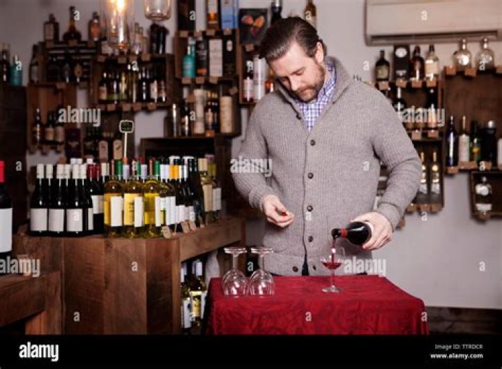 A person pouring wine in a glass A person pouring wine in a glass